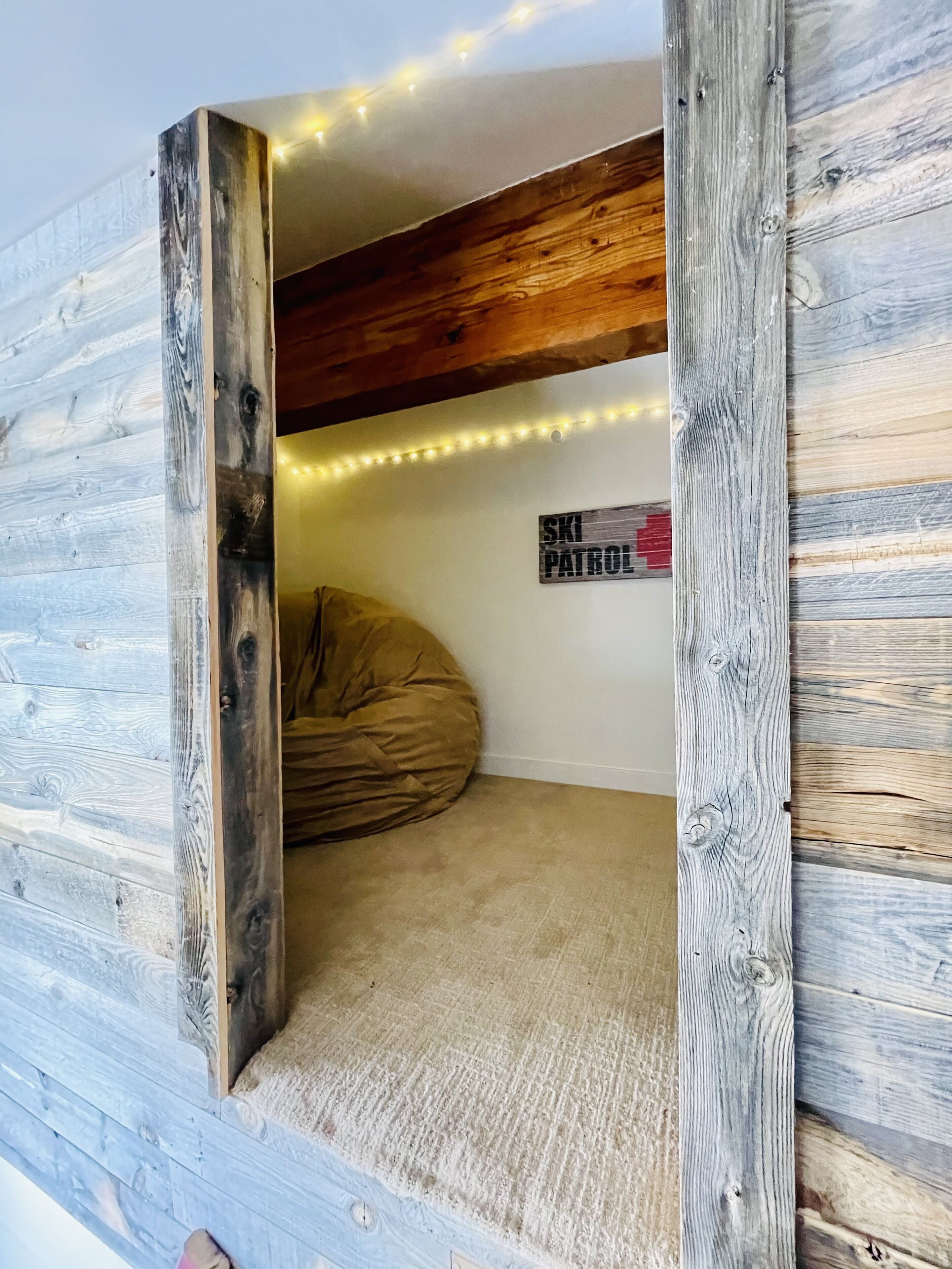 Ein gemütliches Zimmer mit einer Wand aus Holzlamellen, einem Sitzsack und einem Schild mit der Aufschrift 'Ski Patrol'.