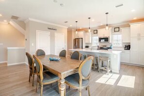 A modern kitchen with white cabinetry, a central island, and pendant lighting.