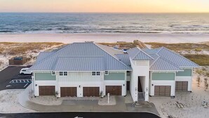 Un bâtiment situé sur la côte, doté de plusieurs garages et d’un parking, et qui se trouve à proximité d’une plage, offrant une vue dégagée sur l’océan.