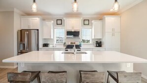 Une cuisine moderne avec des meubles blancs, un grand îlot central et des tabourets de bar.