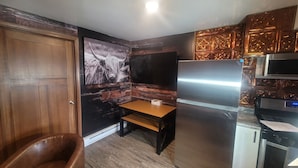Una cocina compacta con puerta de madera, un banco, un refrigerador y un microondas.