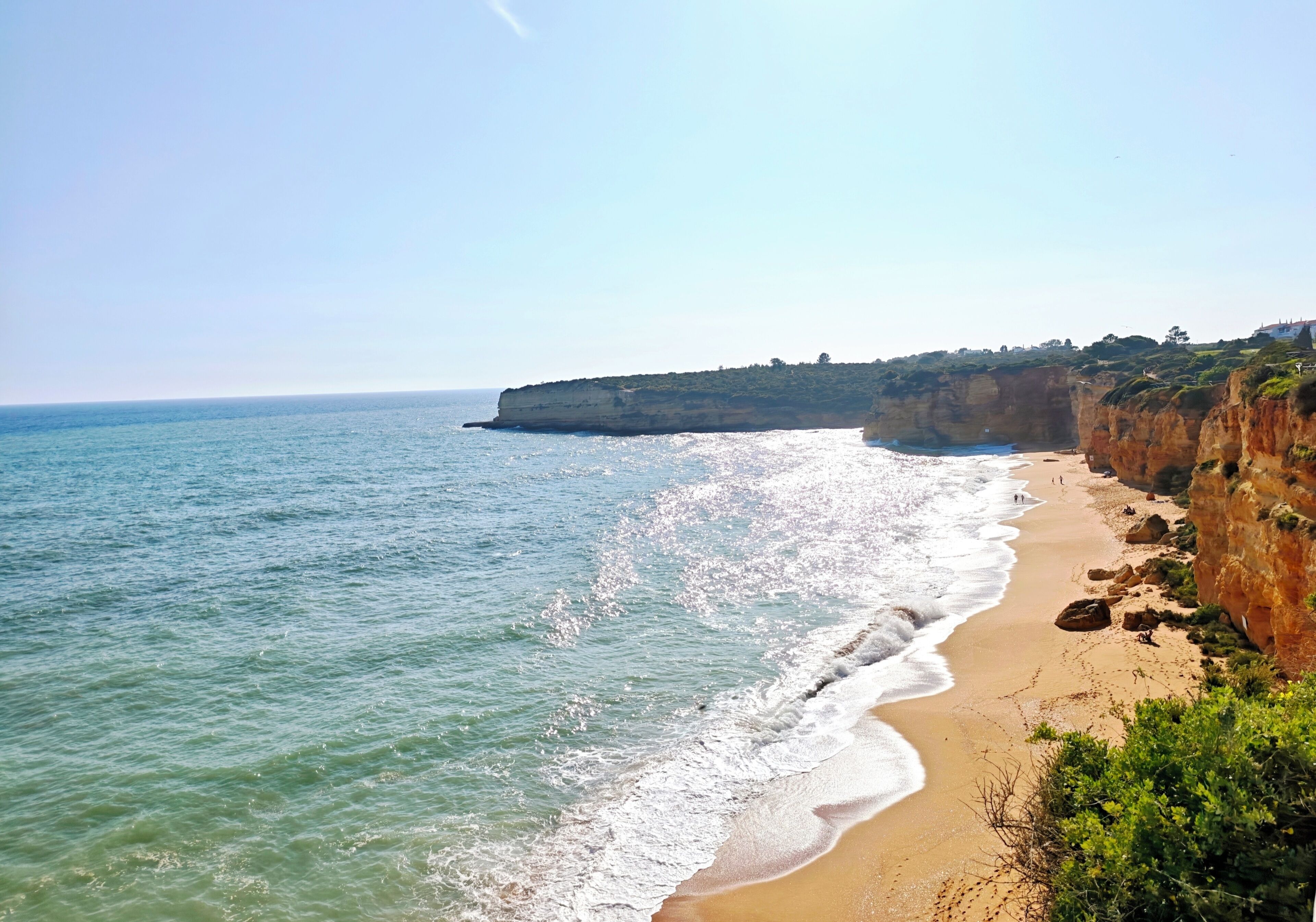 Una spiaggia costiera con acque limpide, una riva sabbiosa e scogliere rocciose.