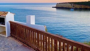 A wooden deck overlooking a calm sea with a sailboat, cliffs, and a clear sky. - A vacation not to be missed with an adult pool / a children's pool, close to the beach (Porches)
