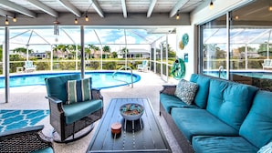 An outdoor patio with a pool, wicker furniture, and a view of the surrounding landscape. - Villa Tropical Vibes - Charming 3 BR waterfront Villa with heated pool, bicycles, fishing poles - walking distance to bars and restaurants (Cape Coral)