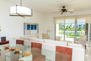 Un salon moderne avec une table basse en verre, un canapé blanc et un ventilateur de plafond.