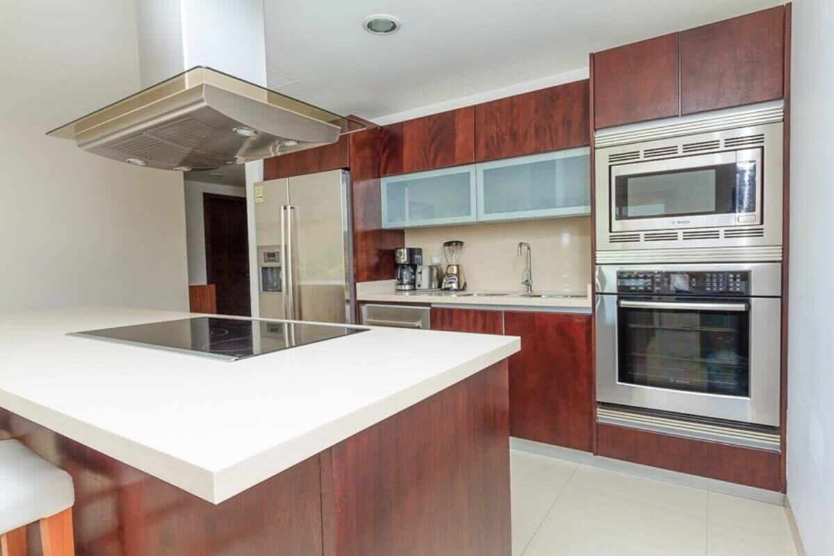 A modern kitchen with a central island, stainless steel appliances, and wooden cabinetry.