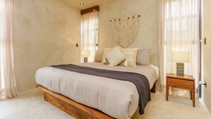 A bedroom with a large bed, a wooden headboard, a macrame wall hanging, and a bedside table with a lamp. - Jungle-View Rooftop Retreat | La Veleta Sanctuary (Tulum)