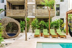Ein modernes Gebäude mit Pool, Liegestühlen und einer Hängematte.