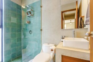 Ein Badezimmer mit Duschkabine, Toilette, Waschbecken und Spiegel.