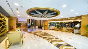 Eine Hotelhalle mit modernem Design, ausgestattet mit einer zentralen Sitzecke, einer Rezeption und einer dekorativen Decke.