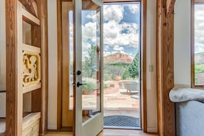 Enjoy the serene views from the patio, featuring a seating area and lush greenery, accessible through a sliding glass door.