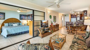 A spacious living room with a large bed, a TV, a dining area, and a kitchen.