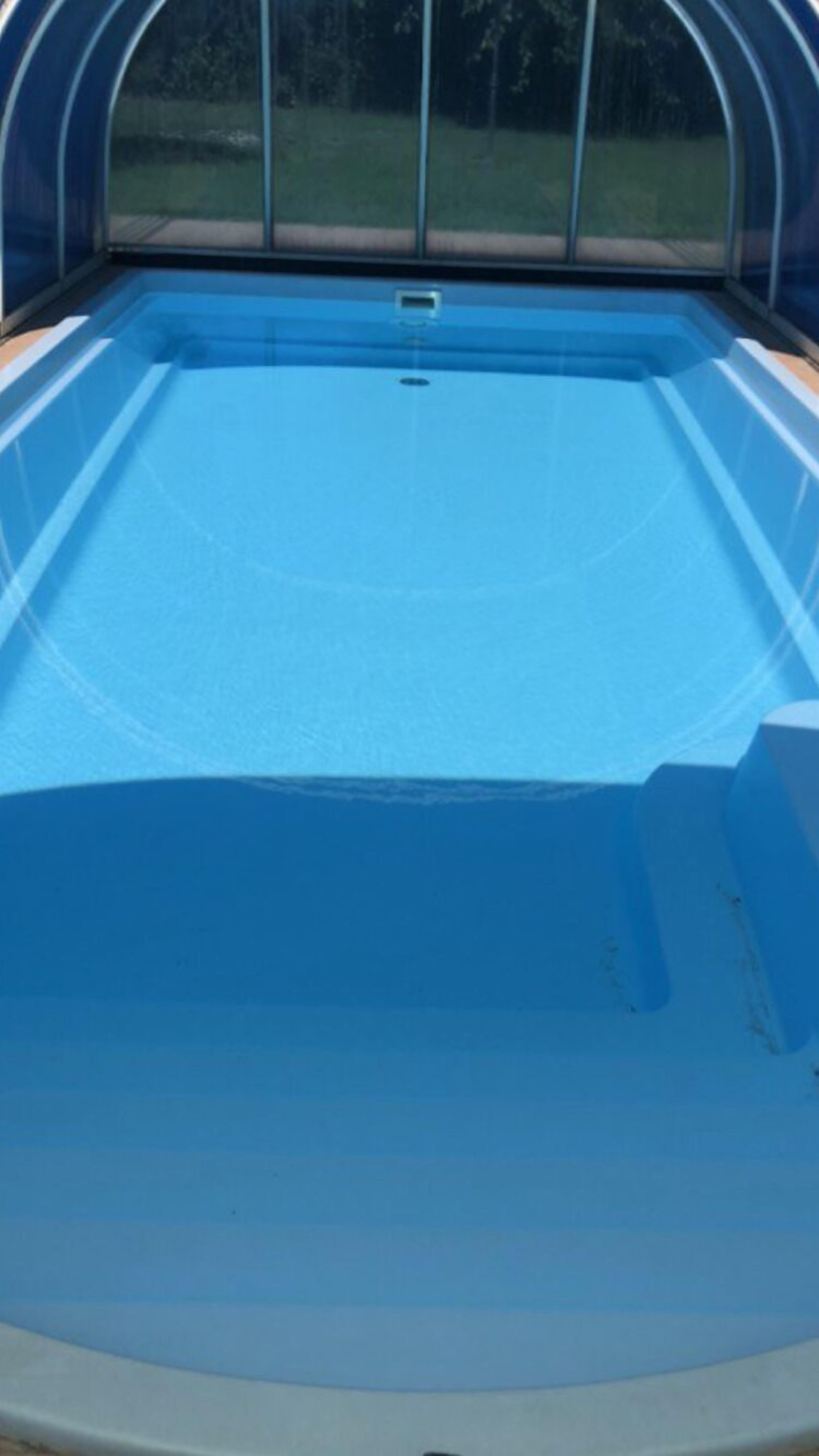 Una piscina vuota con acqua cristallina e blu, circondata da una struttura coperta.