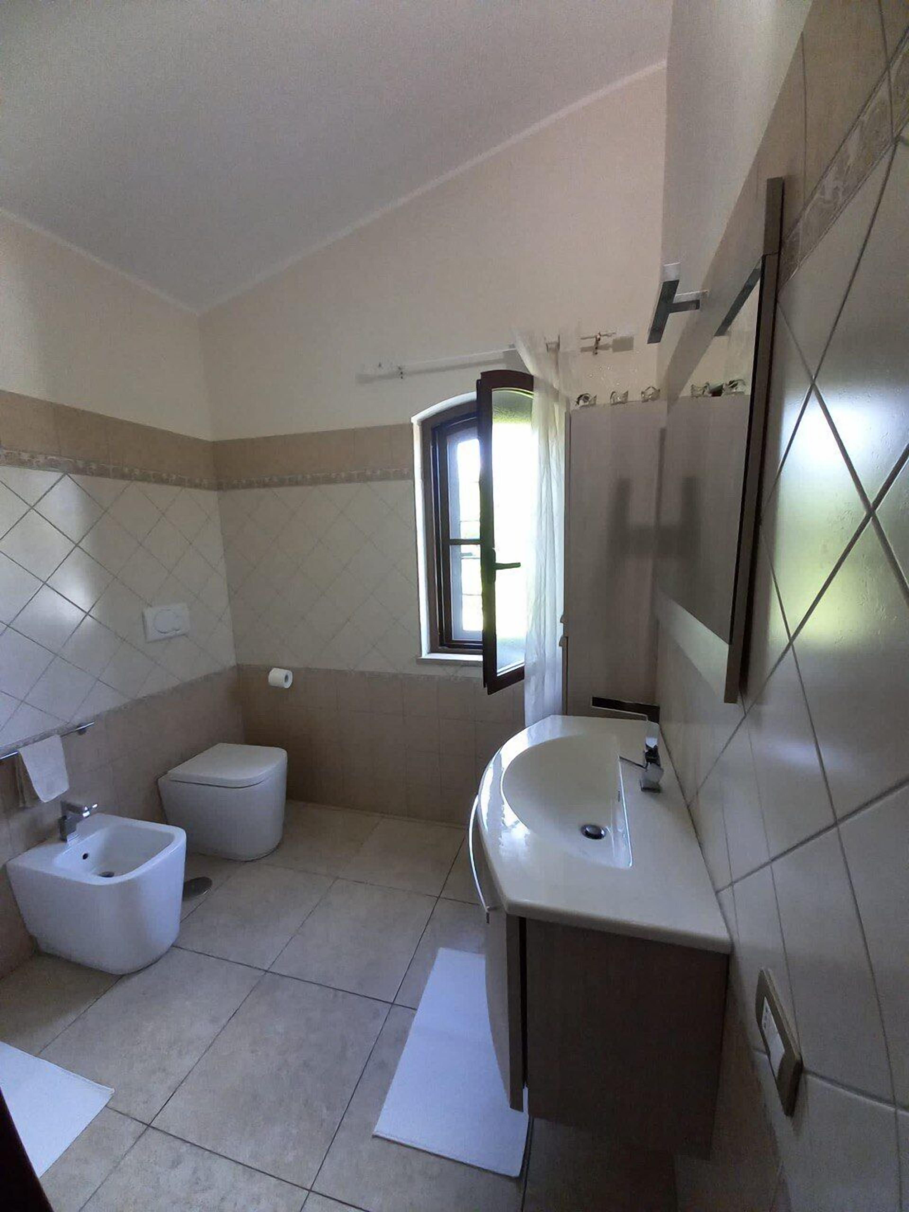 A bathroom with a toilet, bidet, sink, and a mirror.
