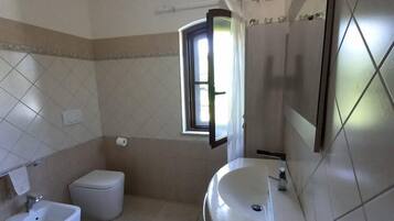 A bathroom with a toilet, bidet, sink, and a mirror.