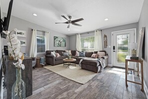 A spacious living room with a gray sofa set, a coffee table, and a ceiling fan.