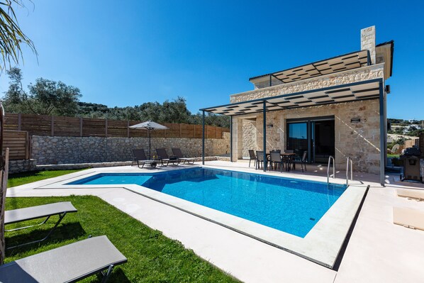 Ein Swimmingpool mit Liegestühlen und einer überdachten Terrasse.