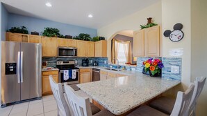 A modern kitchen with wooden cabinets, stainless steel appliances, and a granite countertop. - Lakefront Windsor Hills - 6 Bed 4 Bath Home with Custom Mickey Mouse Heated Pool (Kissimmee)