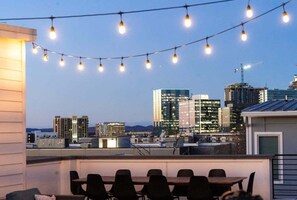 A rooftop terrace with a dining area, string lights, and a city skyline view. - Commodore - Rooftop fire pit & skyline views (Nashville)