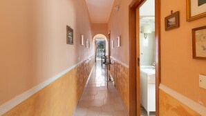 A hallway with a tiled floor, framed pictures on the walls, and a door leading to a bathroom. - Villino Valentina by BarbarHouse (Torre Lapillo)