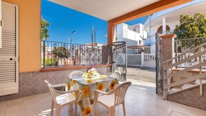 A balcony with a table and chairs, a staircase, and a view of the street and buildings. - Villino Valentina by BarbarHouse (Torre Lapillo)