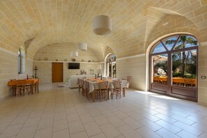 A spacious dining area with a high arched ceiling and large windows.