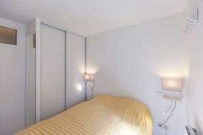 Een slaapkamer met een bed, een kledingkast en twee wandlampen.