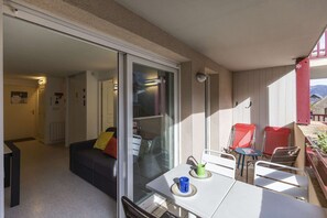 A balcony with a table, chairs, and a sliding glass door leading to a living area.