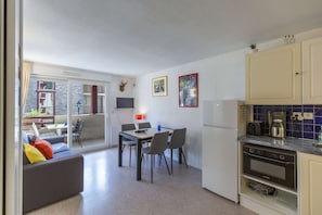 Een kleine keuken met een eethoek, een bank en uitzicht op een balkon.