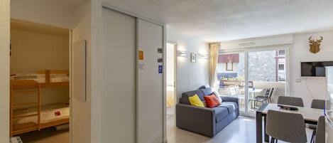 A compact living space with a sofa, a dining table, and a kitchenette.