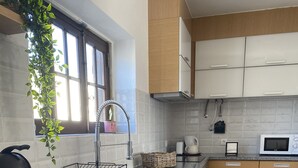Una cuina moderna amb rentadora integrada, un rentaplatets, microones i armaris de fusta.
