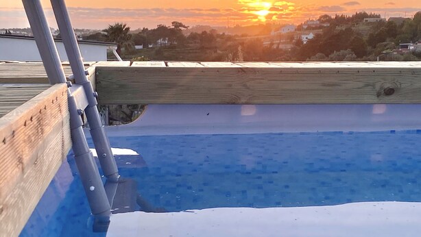 Una piscina amb un solàrium de fusta i baranes metàl·liques.
