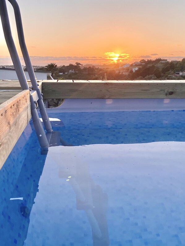 Uma piscina com deck de madeira e grades de metal.