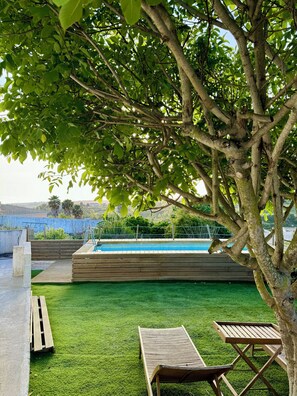 Uma área de piscina com espreguiçadeiras de madeira e uma piscina pequena.