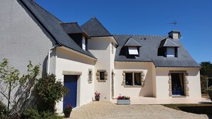 A two-story house with a steeply pitched roof, stone accents, and a gravel driveway.
