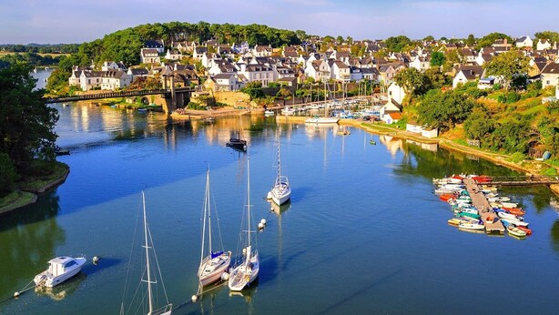 A riverside town with a marina filled with sailboats and yachts.