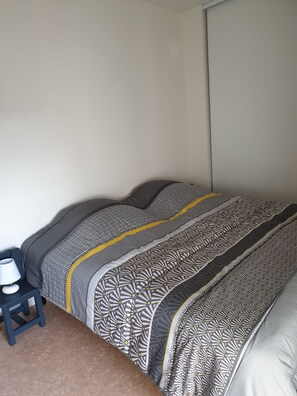 A bedroom with a bed, a nightstand, and a lamp. - Appartement Avec Terrasses, Équipements Entièrement Neufs (Crozon)