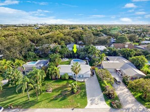 An aerial view of a residential area with houses, a swimming pool, and lush greenery. - The Pelican Villa | Large Pool + Firepit! (West Palm Beach)