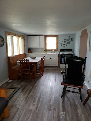 Enjoy dining and relaxation in this well-organized room with a kitchenette, wooden dining table, and comfortable seating.