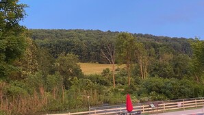 Un'area esterna recintata con piscina, un tavolo e sedie, e un ombrellone rosso.