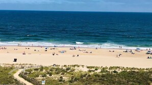 Une plage où l’on peut se prélasser au soleil et se baigner, un rivage sablonneux et un ciel bleu dégagé.