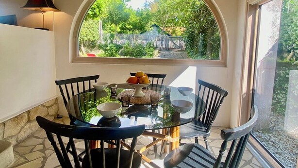 A dining area with a round glass table, black chairs, and a wooden ceiling. - Quartier des Abatilles, Maison des Années 50 Rénovée, Proximité Plages, Forêt (Arcachon)