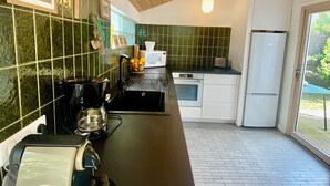 A modern kitchen with a wooden ceiling, a black countertop, and a white refrigerator. - Quartier des Abatilles, Maison des Années 50 Rénovée, Proximité Plages, Forêt (Arcachon)