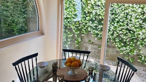 A glass table with chairs, a bowl of fruit, and a hanging light fixture in a room with wooden ceiling and large windows. - Quartier des Abatilles, Maison des Années 50 Rénovée, Proximité Plages, Forêt (Arcachon)
