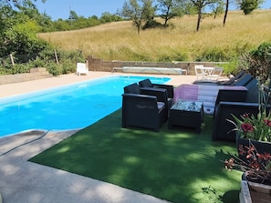 A swimming pool with a patio area, including outdoor furniture and a covered table.