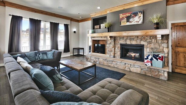 A modern living room with a stone fireplace, a large sectional sofa, and a flat-screen TV mounted above the fireplace.