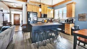 A modern kitchen with wooden cabinets, a central island with stools, and a dining area with a wooden table and chairs.