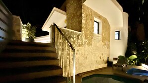 A stone staircase leading to a pool area with a chair and a small table nearby. - Apartamento-casa de Diseño con Entrada Privada y Pequeña Piscina (ses Illetes)