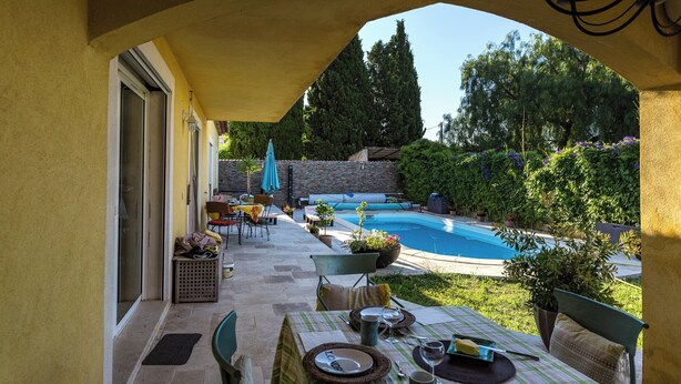 Un patio exterior con una mesa de comedor para dos, una piscina y un muro de piedra.