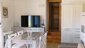A dining area with a table and chairs, a television, and a cabinet. - Villa a 600m dal Mare (Budoni)